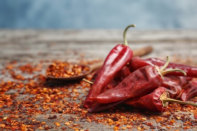 Photo of Dry chili peppers and powder on wooden table