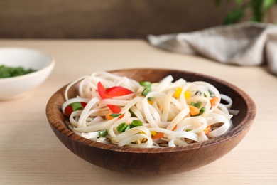 Photo of Bowl of noodles with vegetables on wooden table