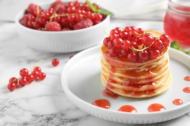 Photo of Delicious pancakes with fresh berries and syrup on white marble table