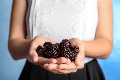 Photo of Woman holding fresh blackberry against color background