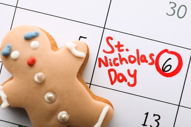 Photo of Gingerbread cookie on calendar page with marked date, top view. December, 6 - Saint Nicholas Day