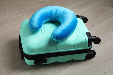 Turquoise travel pillow and suitcase on floor