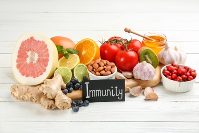 Photo of Card with word Immunity and fresh products on white wooden table