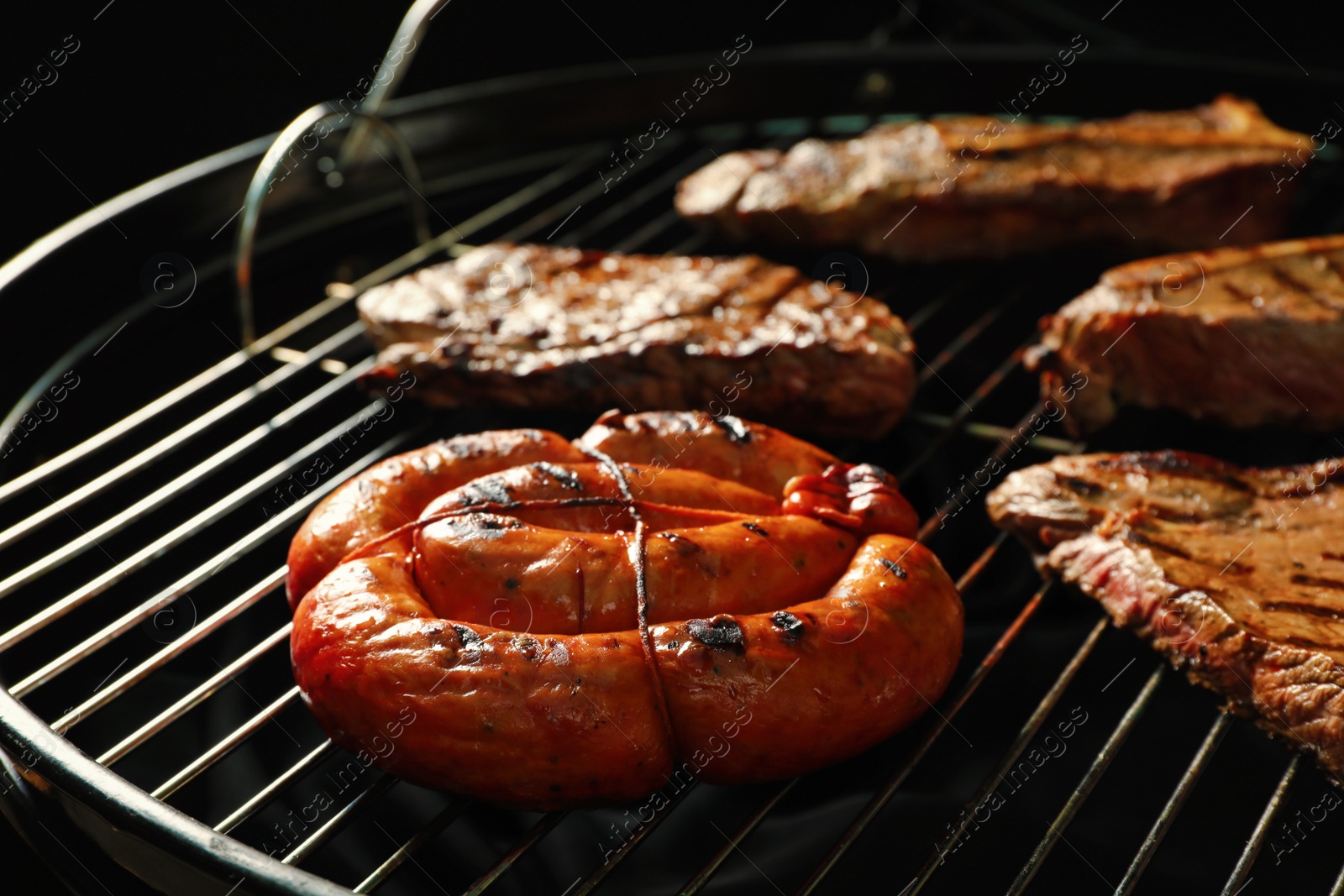 Photo of Fresh grilled tasty meat steaks and sausage on barbecue grate