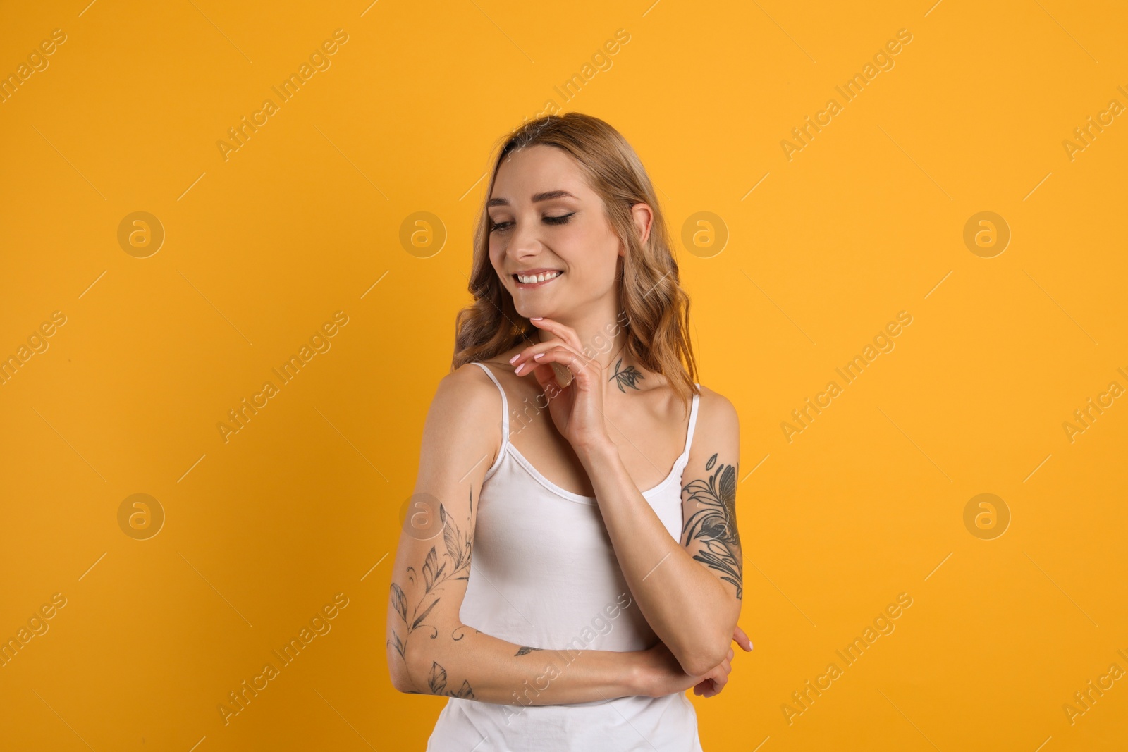 Photo of Beautiful woman with tattoos on body against yellow background