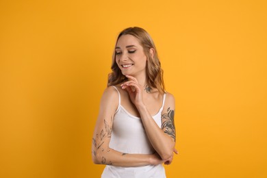 Photo of Beautiful woman with tattoos on body against yellow background