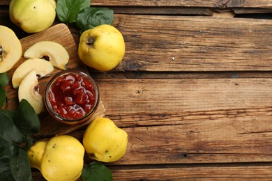 Photo of Delicious quince jam and fruits on wooden table, flat lay. Space for text