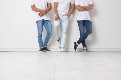 Photo of Group of young men in jeans near light wall