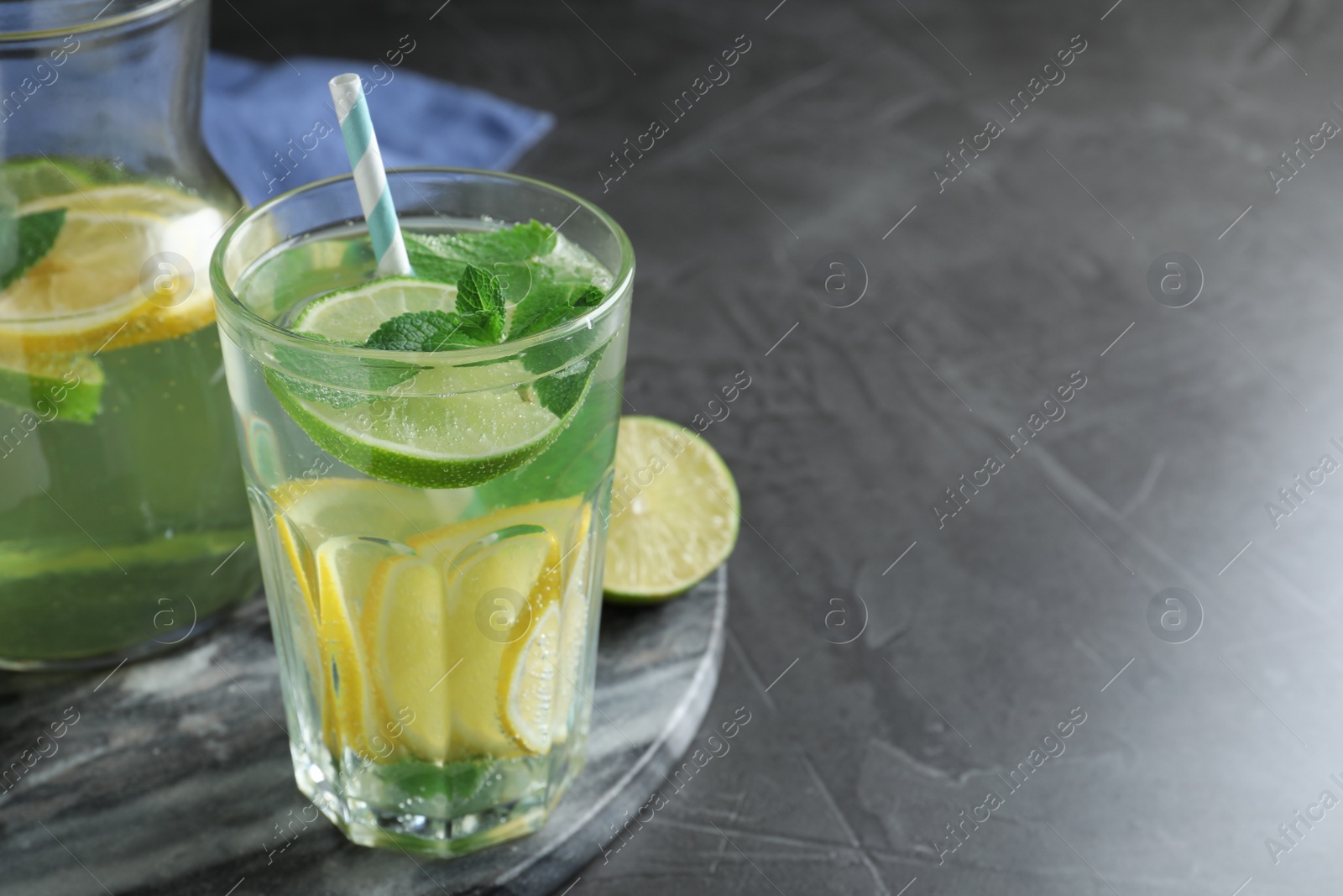 Photo of Delicious lemonade made with soda water and fresh lime on grey table. Space for text