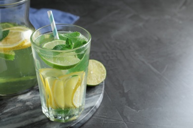 Delicious lemonade made with soda water and fresh lime on grey table. Space for text