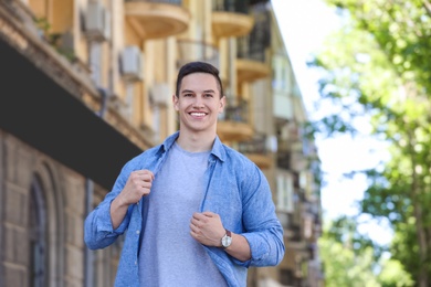 Photo of Young man in stylish outfit outdoors. T-shirt as mockup for design