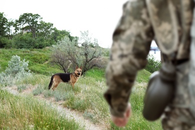 Man in military uniform with German shepherd dog outdoors