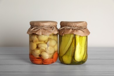 Photo of Jars with different preserved vegetables on wooden table