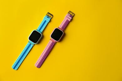 Kid smart watches on yellow background, flat lay. Space for text