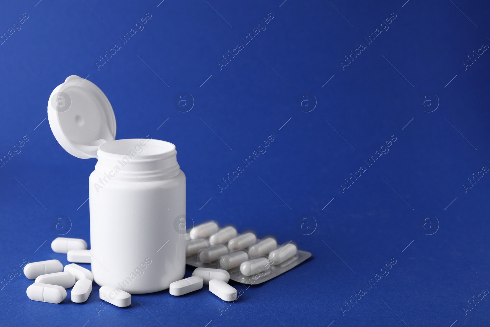 Photo of Antidepressants and medical jar on blue background, space for text