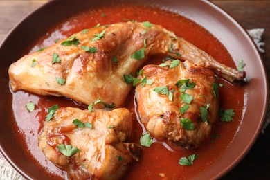 Tasty cooked rabbit meat with sauce and parsley on table, closeup