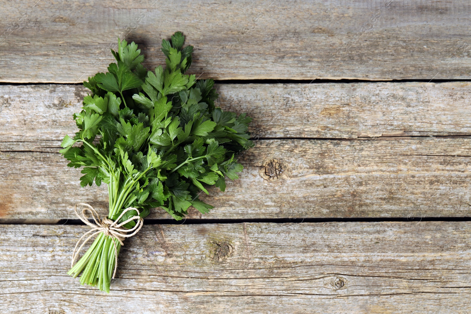 Photo of Bunch of fresh green parsley leaves on wooden table, top view. Space for text