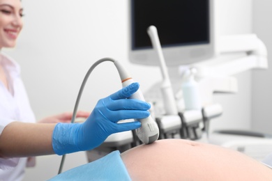 Pregnant woman undergoing ultrasound scan in clinic, closeup