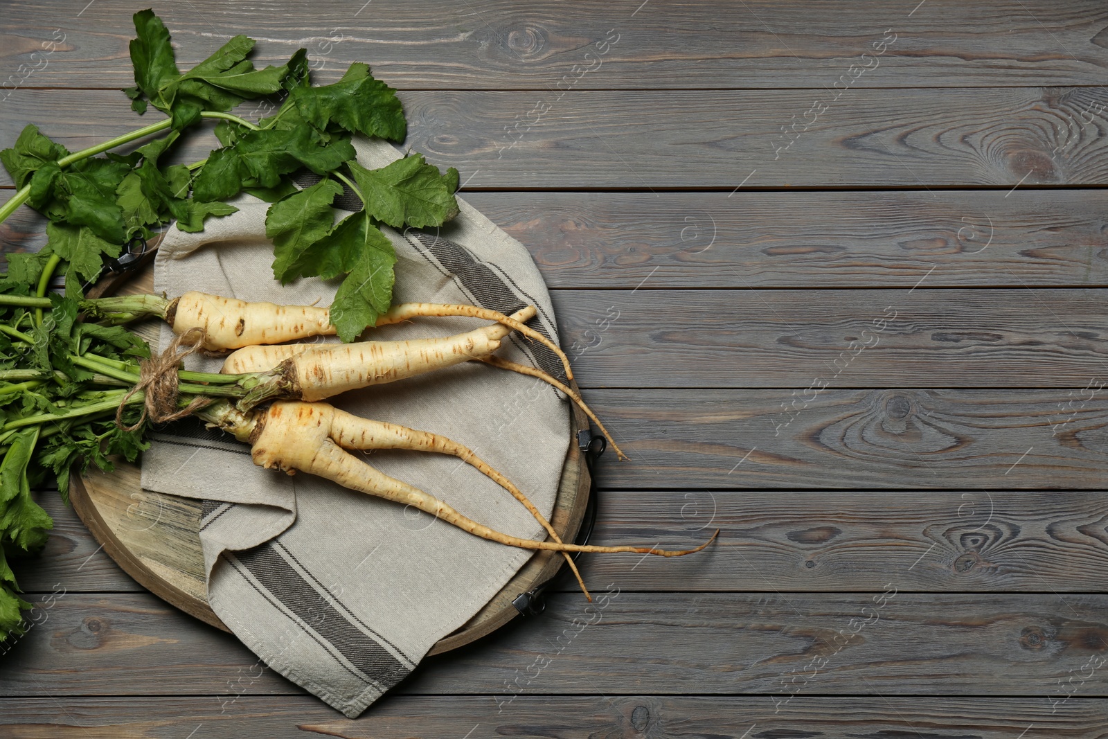 Photo of Tasty fresh ripe parsnips on grey wooden table, top view. Space for text