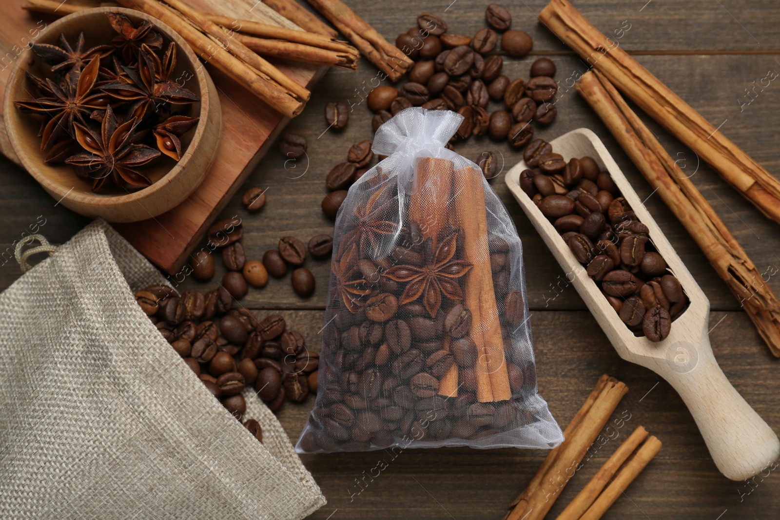 Photo of Scented sachet with coffee beans, anise and cinnamon on wooden table, flat lay