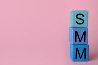 Photo of Blue cubes with abbreviation SMM (Social media marketing) on pink background. Space for text