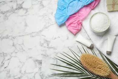 Photo of Flat lay composition with shower caps and toiletries on white marble background. Space for text