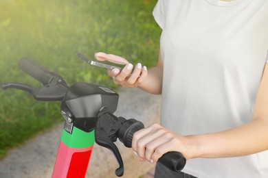 Woman using smartphone to pay and unblock electric kick scooter outdoors, closeup