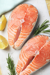 Photo of Fresh raw salmon with lemon and rosemary on parchment, flat lay. Fish delicacy