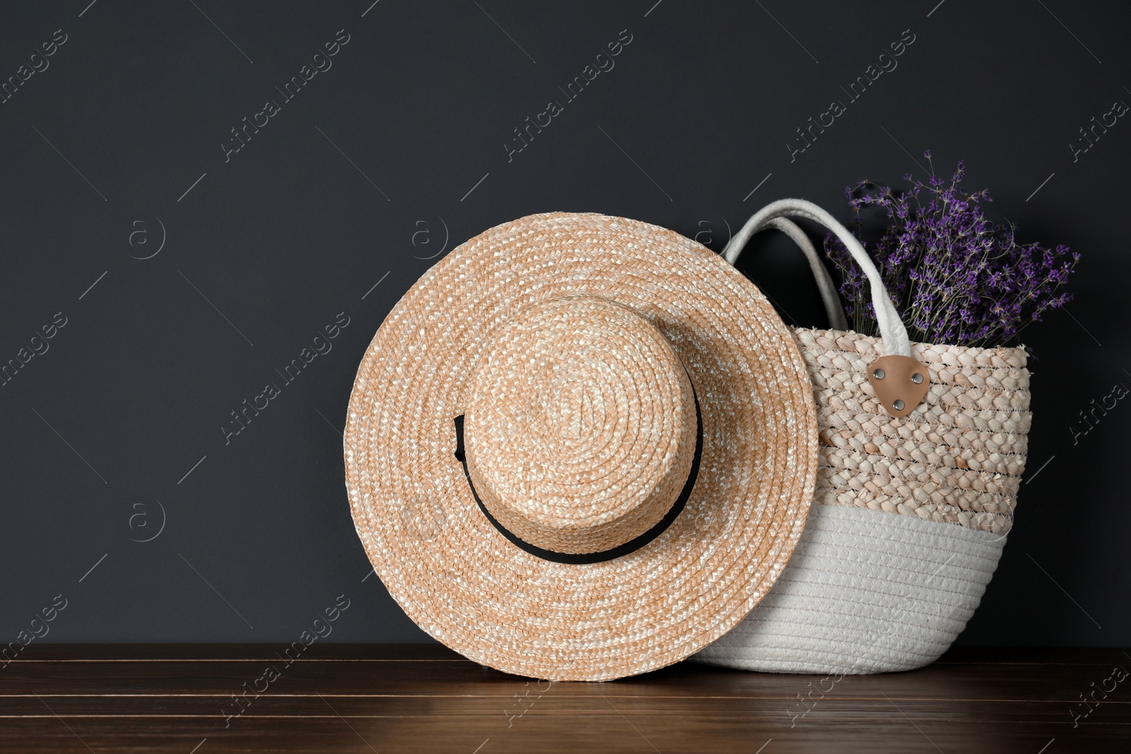 Photo of Straw hat and bag with flowers on wooden table