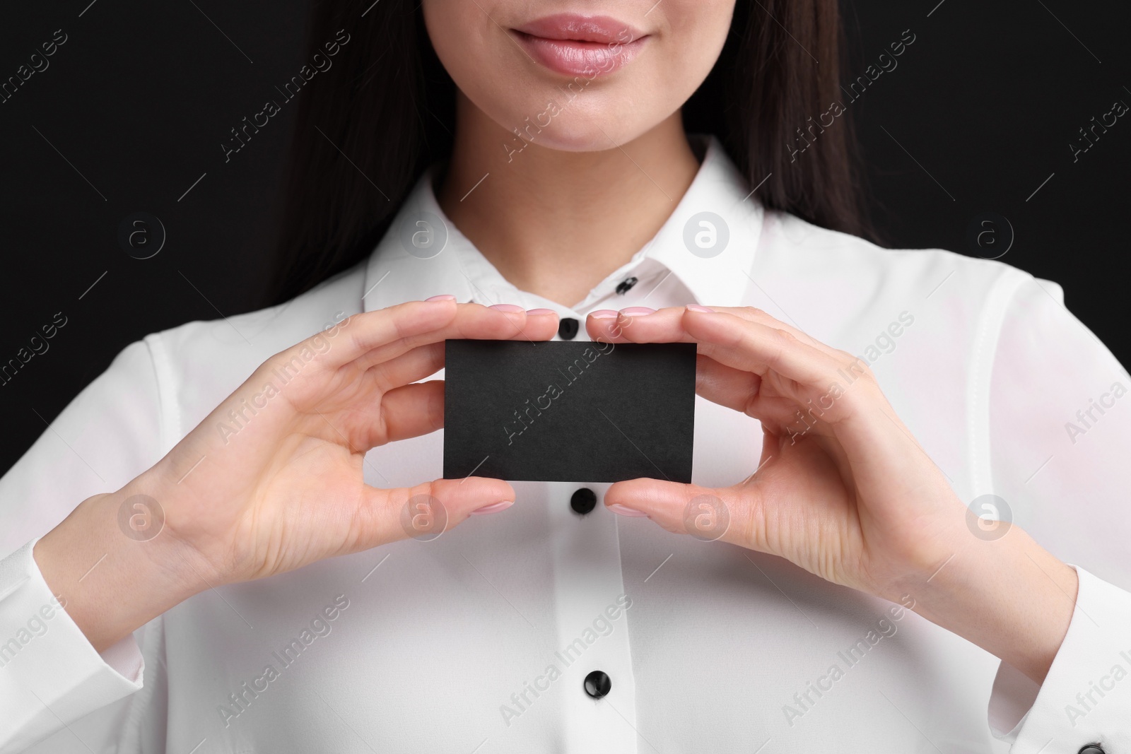 Photo of Woman holding blank business card on black background, closeup. Space for text