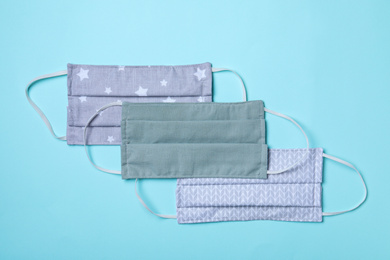 Homemade protective masks on light blue background, flat lay. Sewing idea