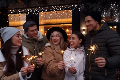 Group of happy friends with sparklers at winter fair