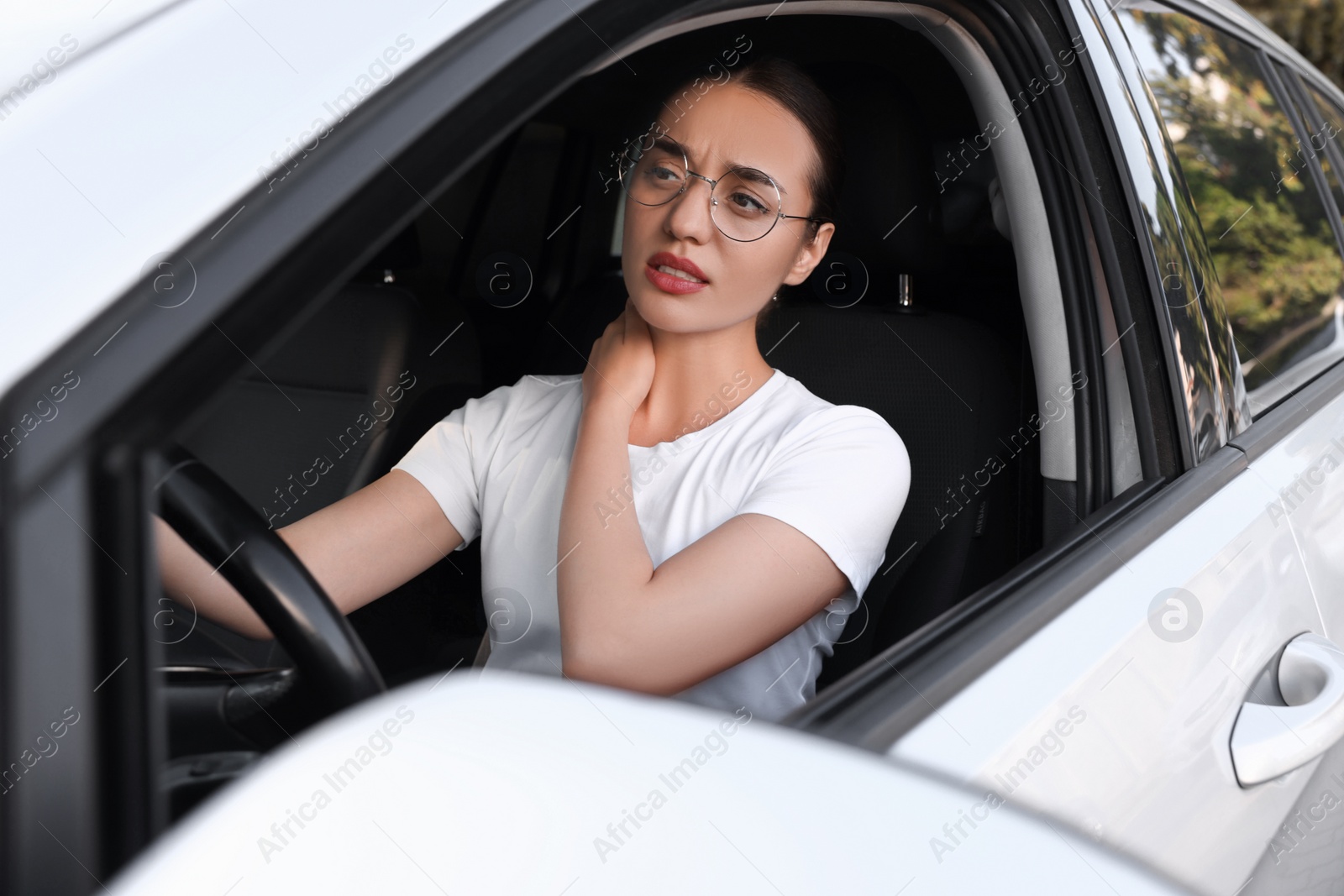 Photo of Young woman suffering from neck pain in her car