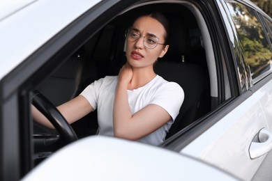 Young woman suffering from neck pain in her car