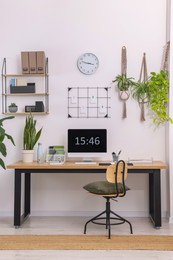 Cozy workplace with computer, modern furniture and houseplants at home