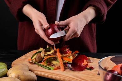 Photo of Woman peeling fresh onion with knife at table, closeup