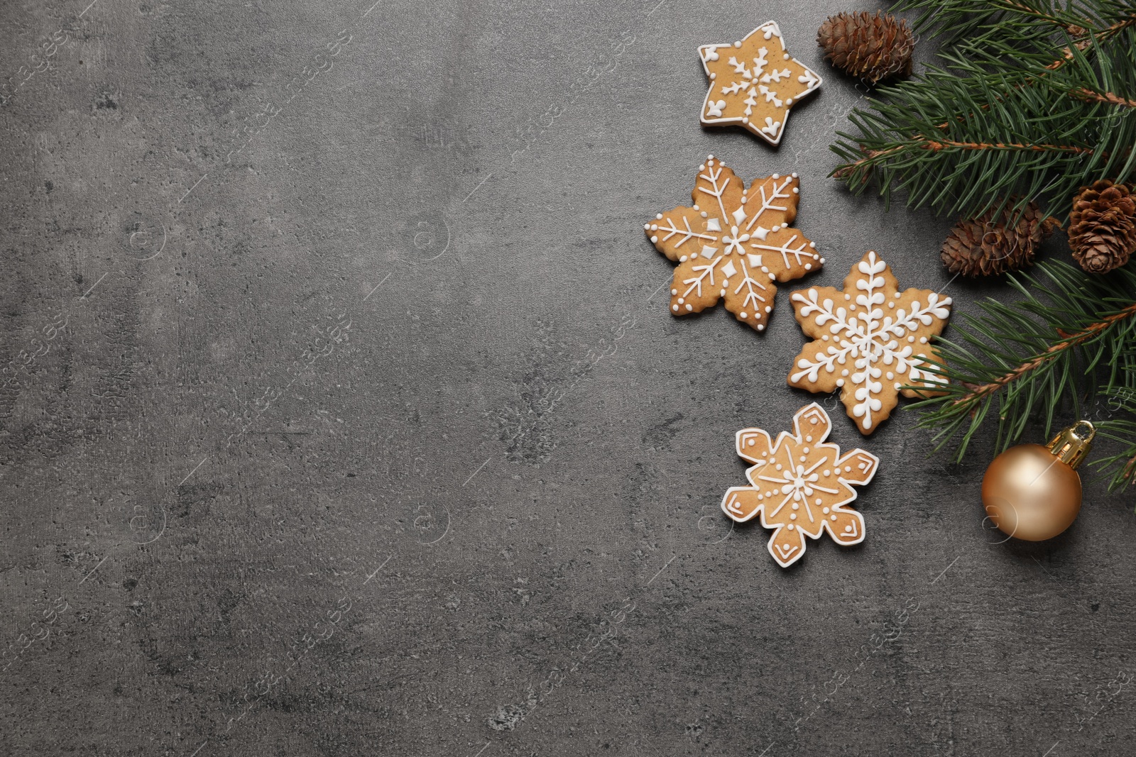 Photo of Tasty Christmas cookies, fir branches and festive decor on grey table, flat lay. Space for text