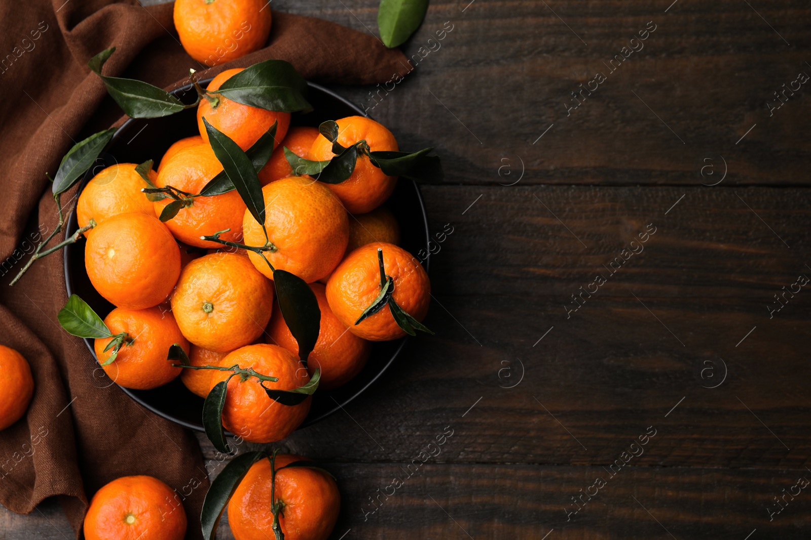 Photo of Fresh ripe tangerines with green leaves on wooden table, flat lay. Space for text