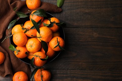 Fresh ripe tangerines with green leaves on wooden table, flat lay. Space for text