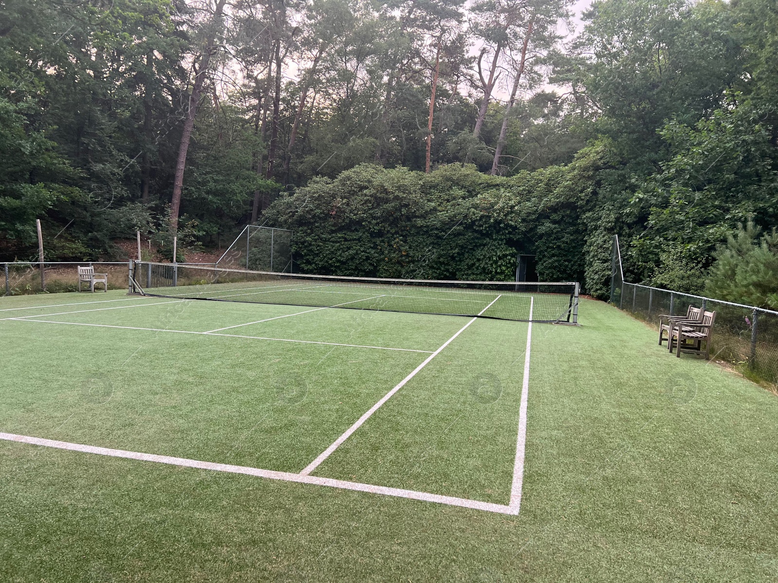 Photo of Tennis court with green grass and net outdoors