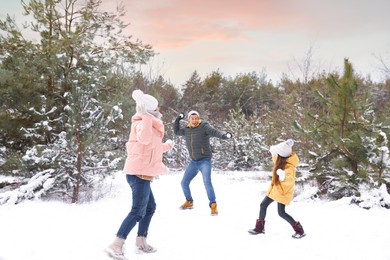 Photo of Happy family having snowball fight outdoors on winter day. Christmas vacation