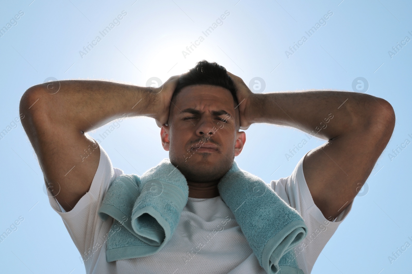 Photo of Man with towel suffering from heat stroke outdoors, low angle view