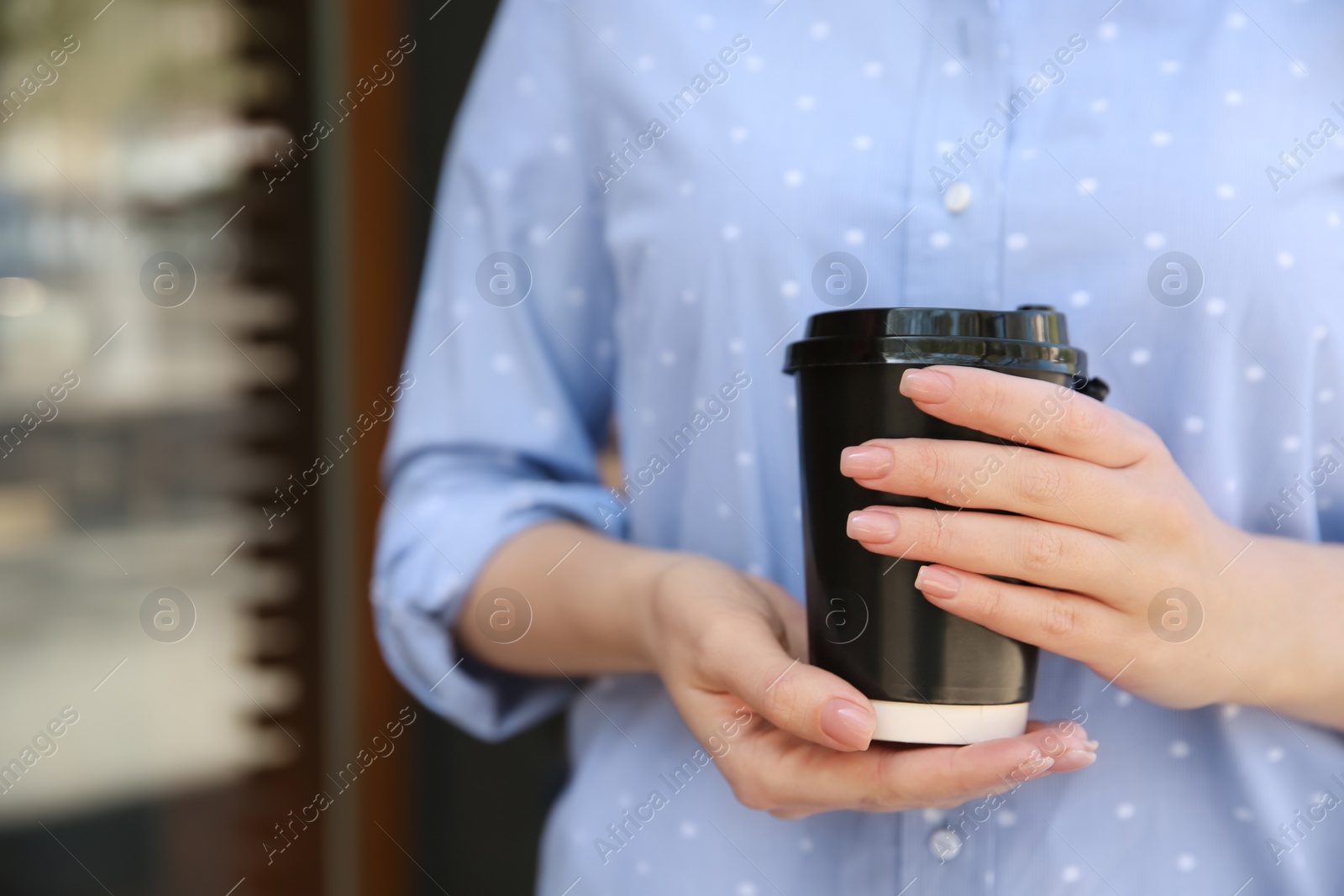 Photo of Woman with takeaway coffee cup outdoors, closeup