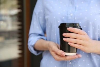 Woman with takeaway coffee cup outdoors, closeup