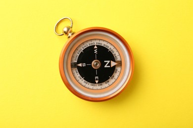 Photo of One compass on yellow background, top view