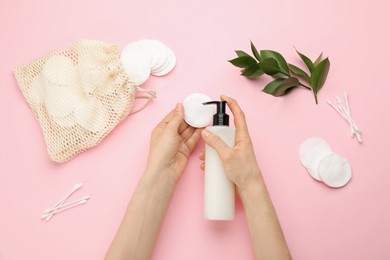 Photo of Woman applying makeup removal product on pink background, top view