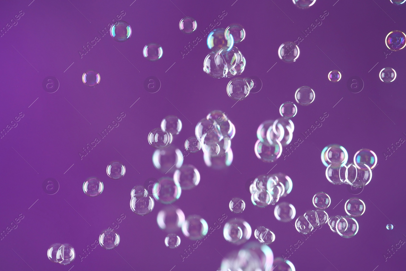 Photo of Beautiful transparent soap bubbles on purple background