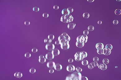 Photo of Beautiful transparent soap bubbles on purple background