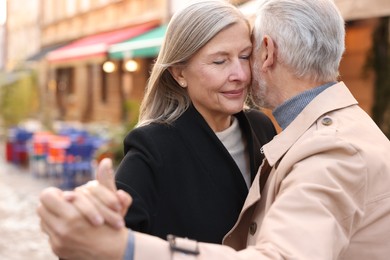 Affectionate senior couple dancing together on city street