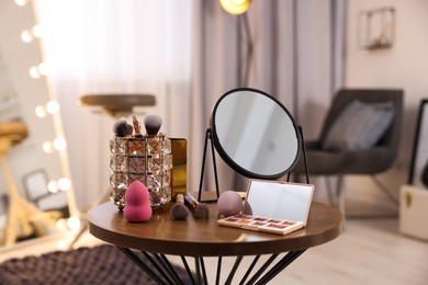 Different beauty products and mirror on wooden table in makeup room